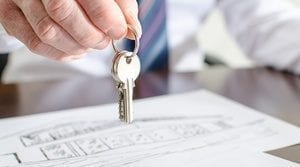 Estate agent holding house keys over a contract